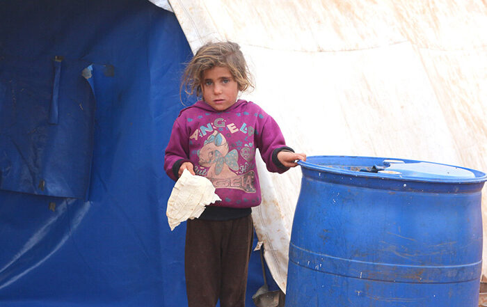 Little girl standing outside a tent in a camp in Syria