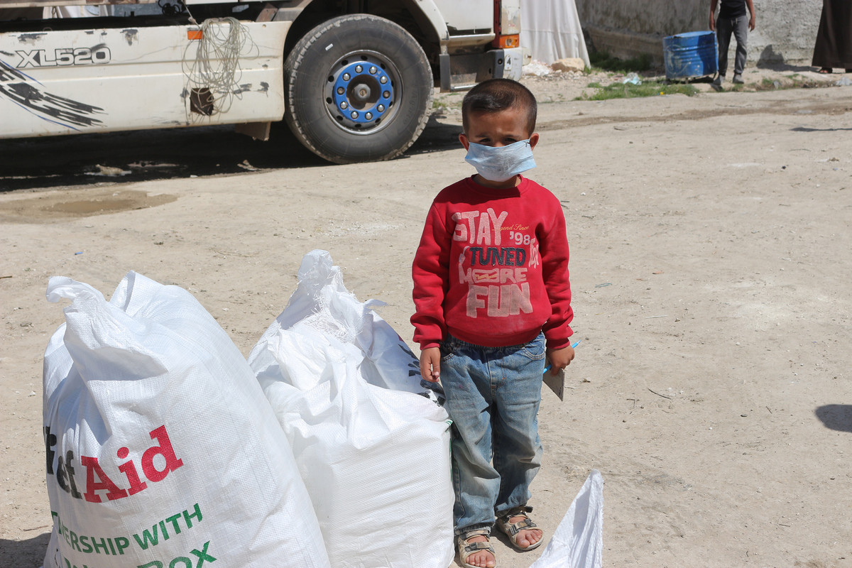 Child in Syria wearing a mask next to ShelterBox aid