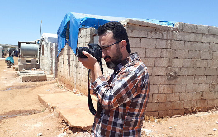 ReliefAid worker Mustafa holding a camera in a Syrian refugee camp