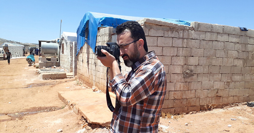 ReliefAid worker Mustafa holding a camera in a Syrian refugee camp