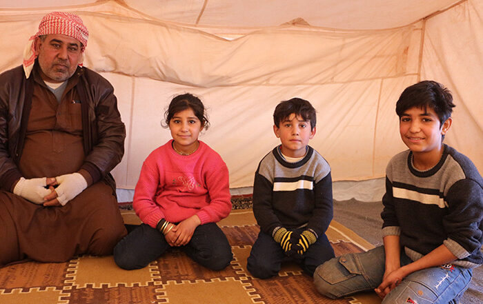 A man and three children in a tent in Syria