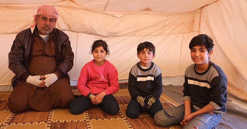 A man and three children in a tent in Syria