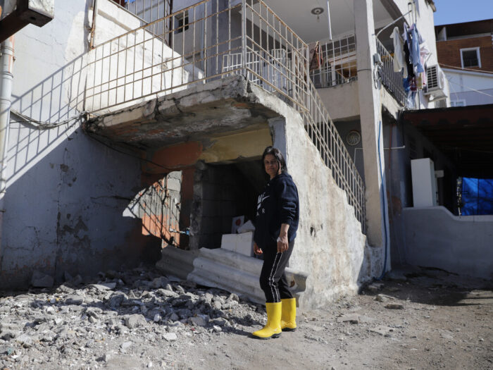 Woman standing next to damaged staircase outside a house in Turkey