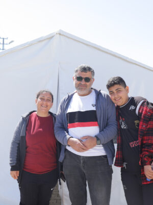 Three people standing in front of a tent after the earthquakes in Turkey