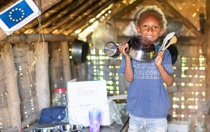 Child holding kitchen pots inside a shelter on Vanuatu