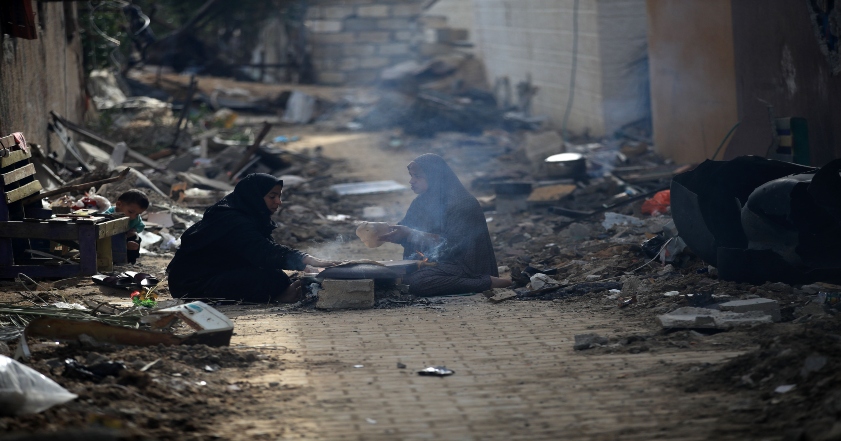 Two women sitting in the street after losing their homes in Gaza