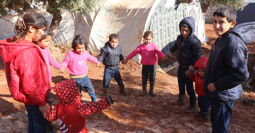 Children wearing winter clothing holding hands in Syria