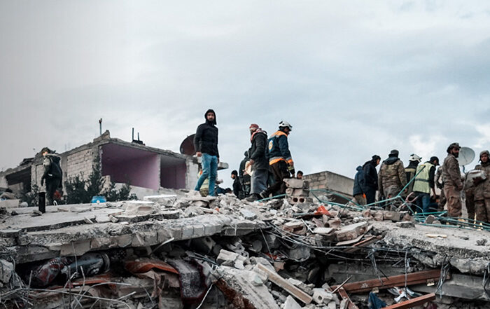 Collapsed building with people standing on rubble