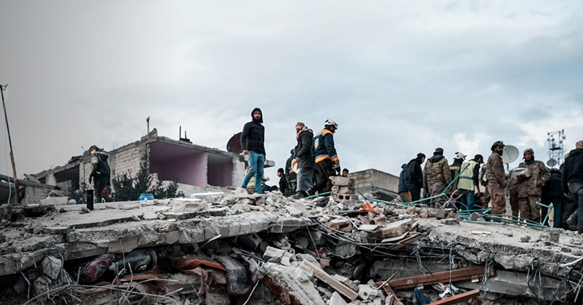 Collapsed building with people standing on rubble