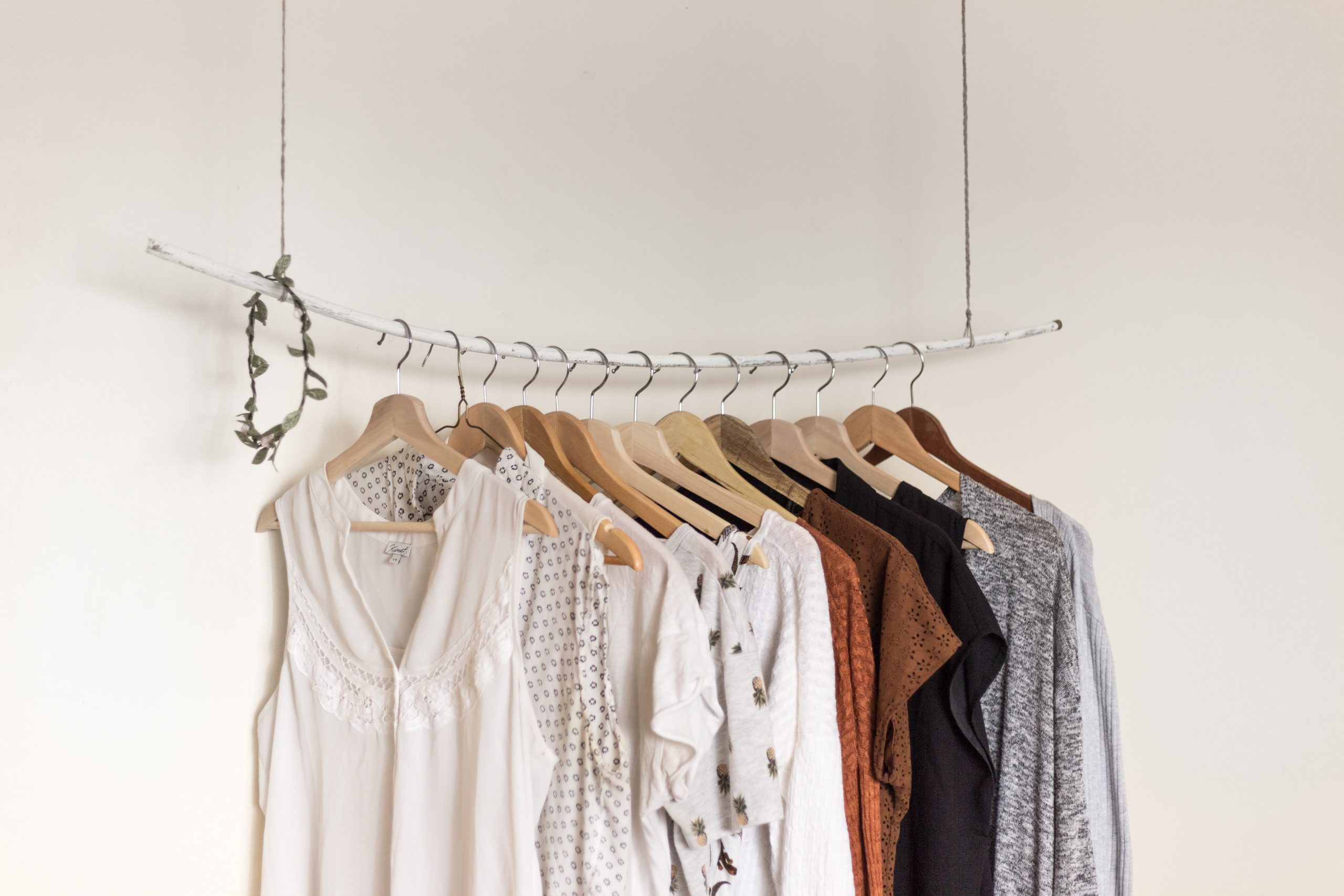 Pieces of clothing on coat hangers hung in a row against a white background