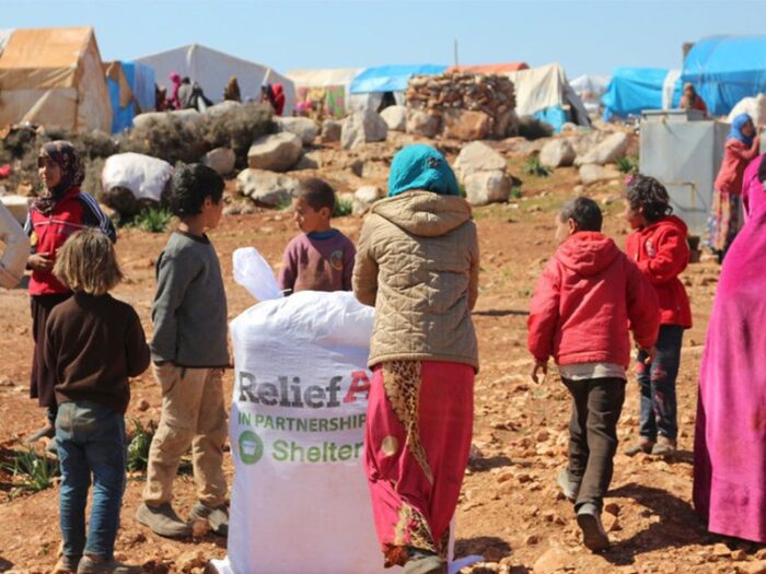 Women and children between shelters with reliefaid package