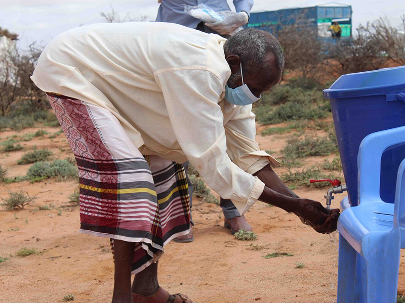 Man in Somaliland wearing a mask and washing his hands