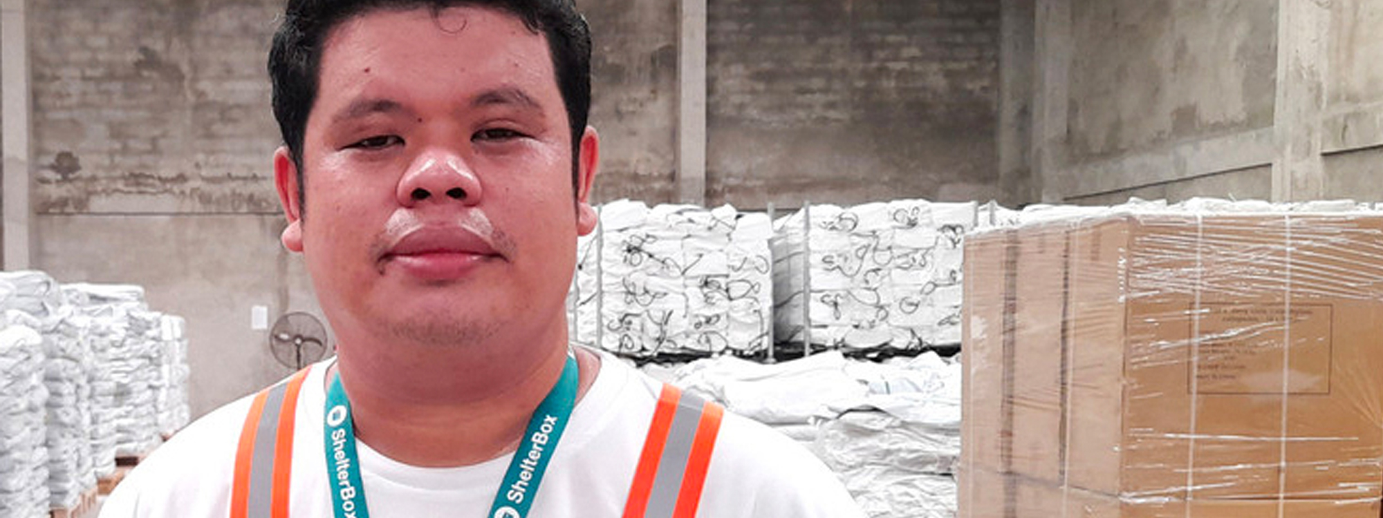 Man standing in front of aid materials in the warehouse at ShelterBox Philippines