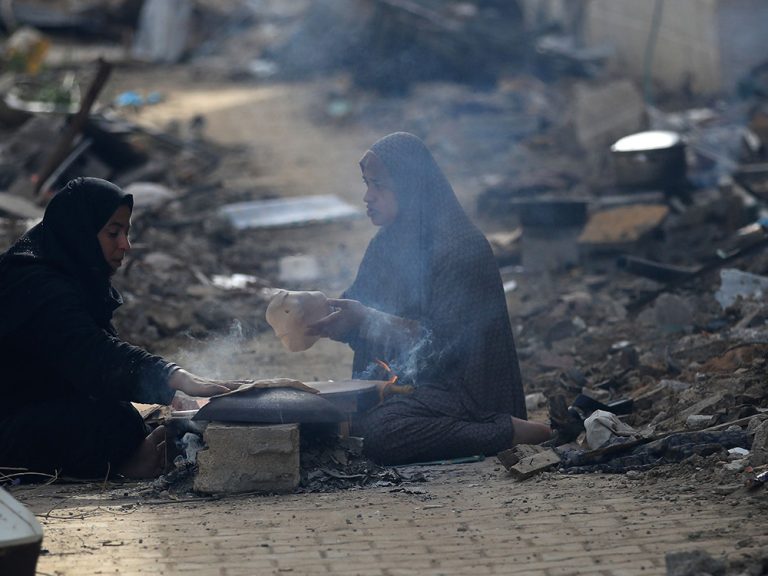 Two women sitting in street after losing their homes in Gaza
