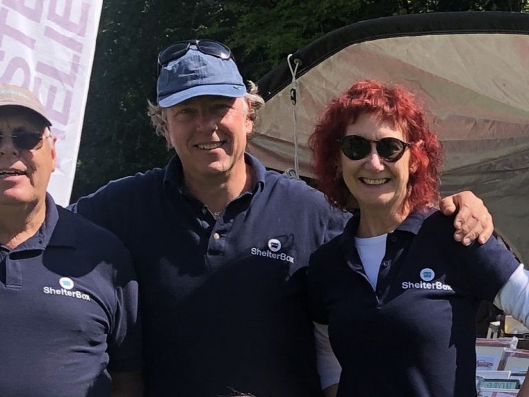 Three people standing outside a ShelterBox tent