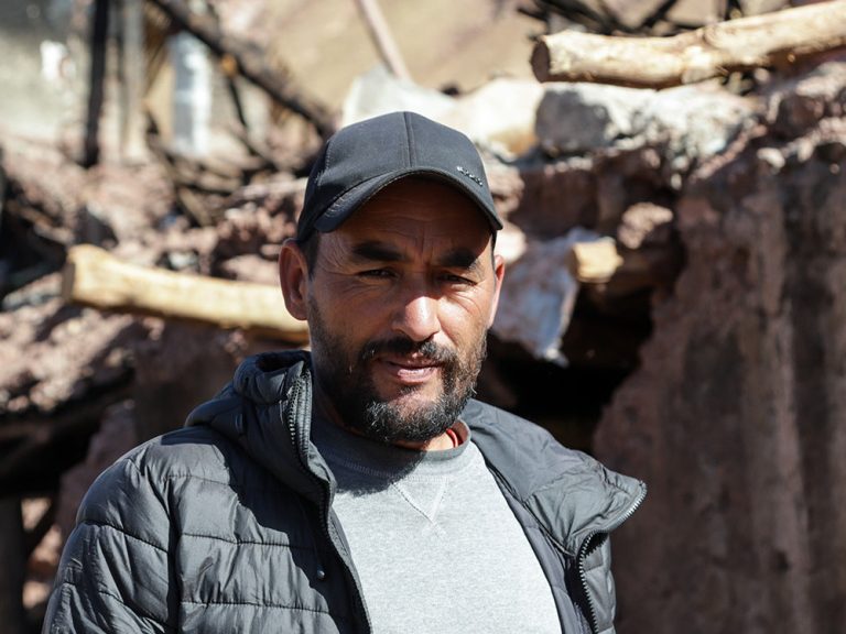 Man standing in remains of a house destroyed in an earthquake in Morocco