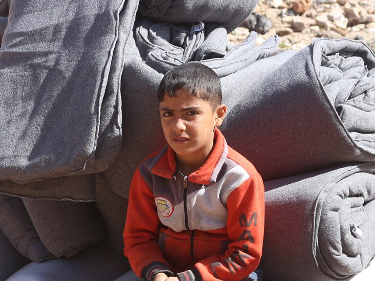Boy sitting with pile of blankets