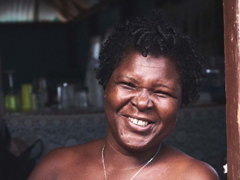 Woman smiling at camera next to a blue door on Dominica in the Caribbean