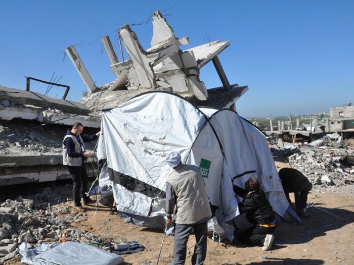 Tent being put up next to a destroyed building in Gaza