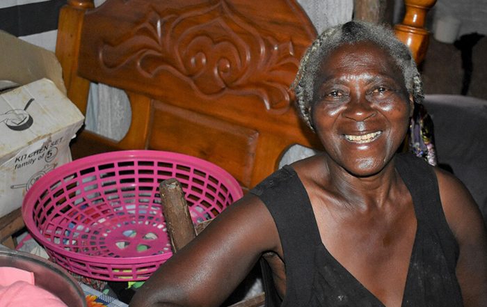 Woman sitting in her home and smiling at the camera in Haiti