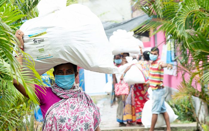 Woman wearing facemask carrying bag of aid on her head