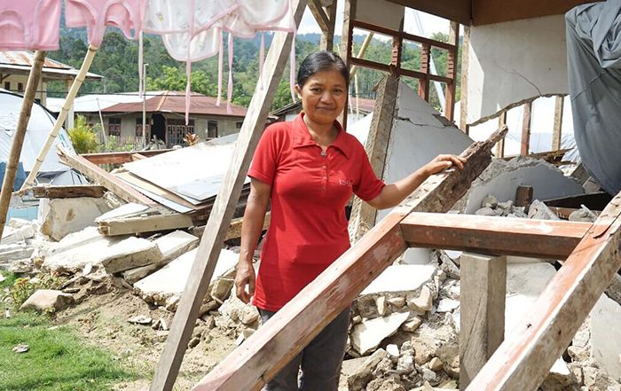 Woman standing in damaged home in Indonesia