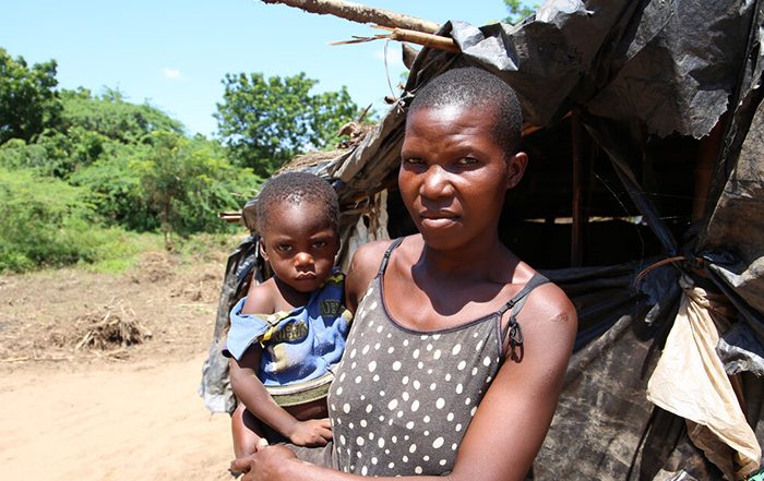 Woman holding a child outside a temporary shelter in Malawi