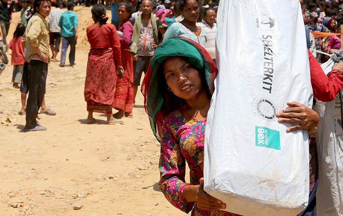 Woman carrying shelter kit among crowds in Nepal