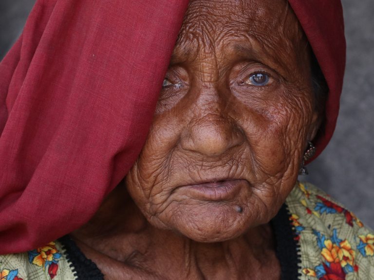 Older lady wearing a red head scarf in Pakistan