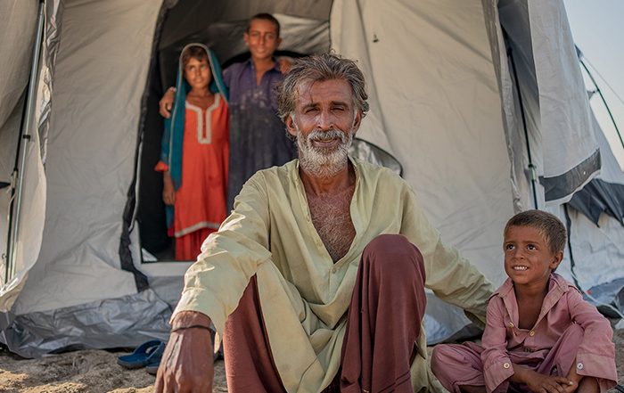 Man and child sit outside a tent in Pakistan