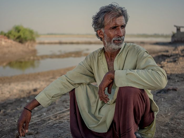 Man crouching in front of flood water in Pakistan