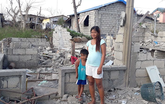 Woman and boy in remains of a destroyed house in the Philippines