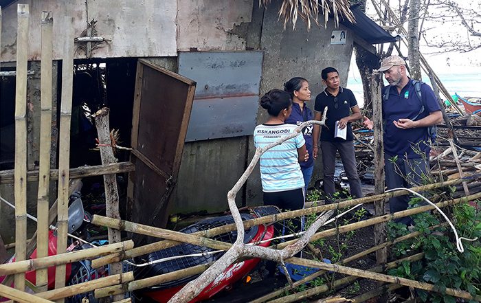 People standing next to damaged building in the Philippines