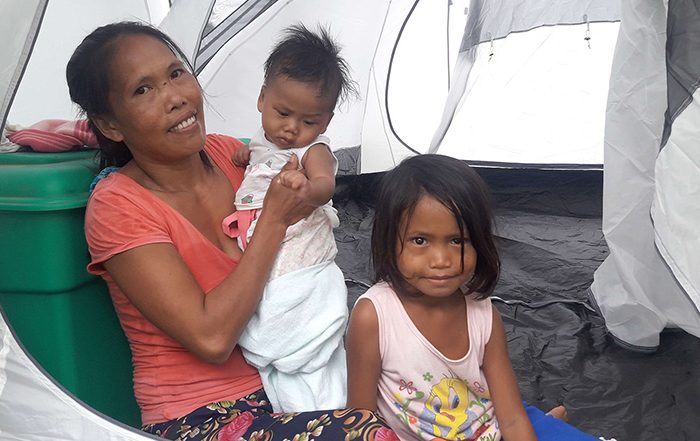 Woman and two children in a tent in the Philippines