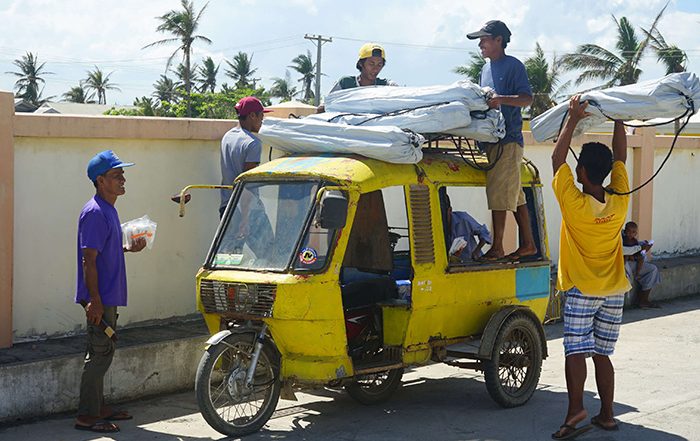 Men unloading aid from yellow rickshaw