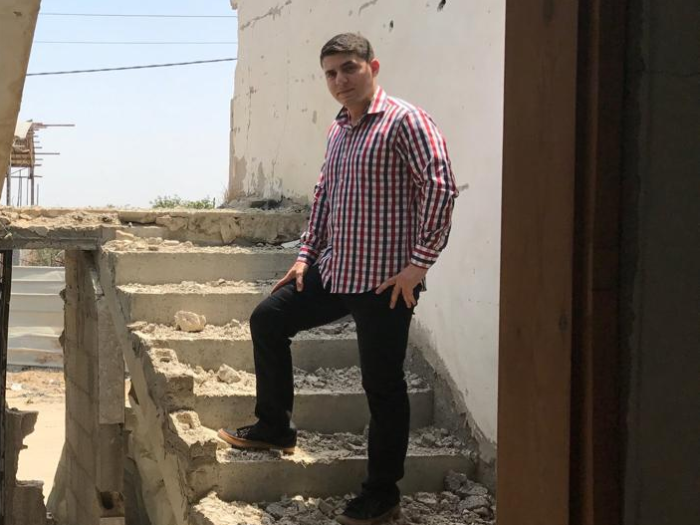 Man standing on stairs in destroyed home in Gaza