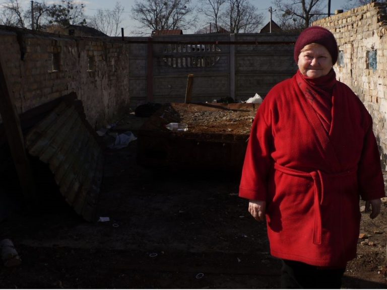 Woman standing in remains of bombed out home in Ukraine