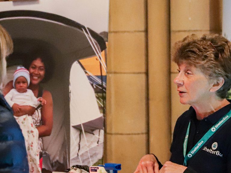 ShelterBox team member and member of the public at a ShelterBox display in Truro cathedral