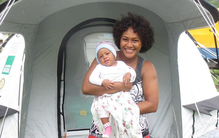 Woman holding baby outside a tent