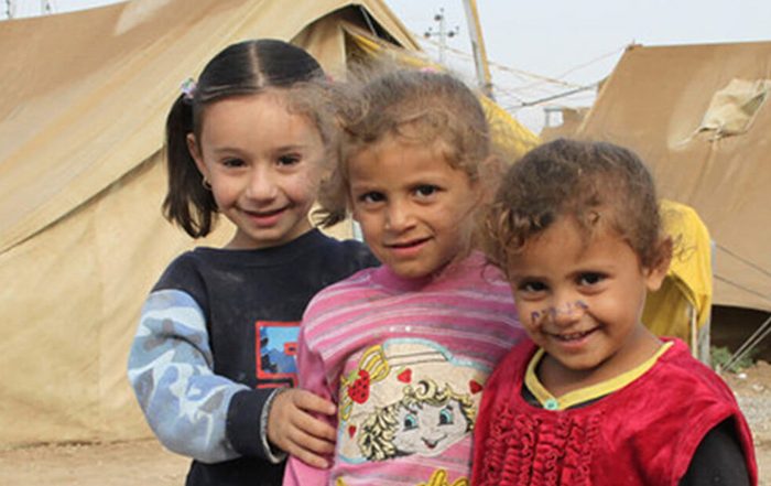 Three girls next to tents in Iraq