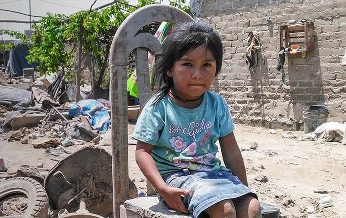 Little girl sitting among rubble in Peru