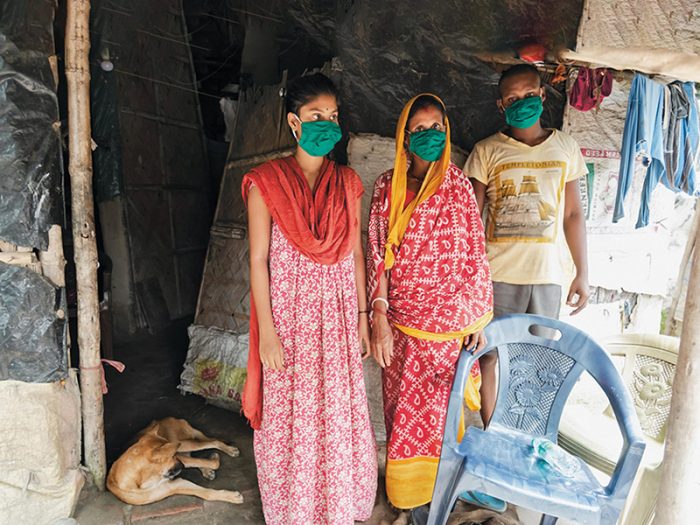 Three people wearing facemasks in a home in India