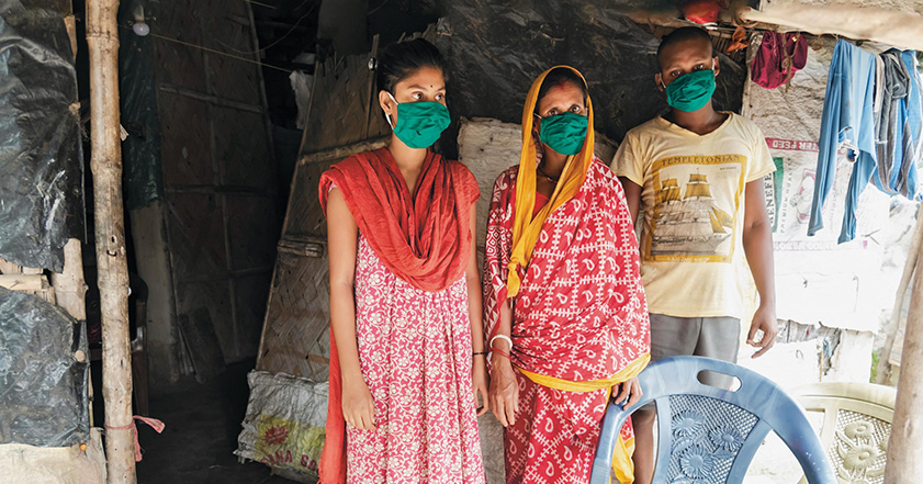 Three people wearing facemasks in a home in India
