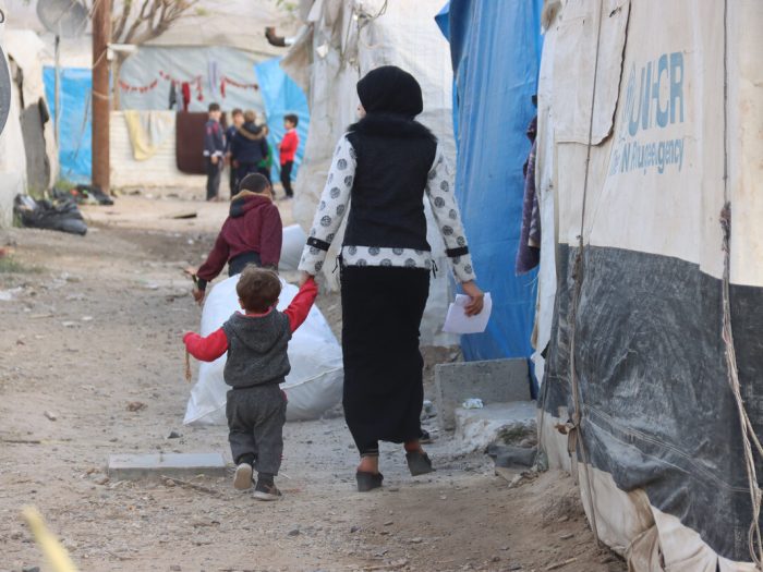 Woman walking with child in a displacement camp in Syria