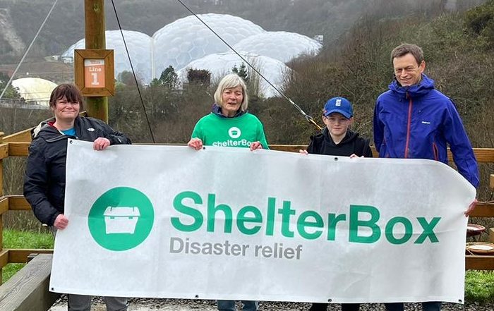 Group of 4 people holding a ShelterBox banner above the Eden Project