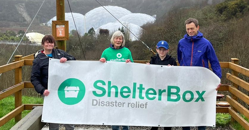 Group of 4 people holding a ShelterBox banner above the Eden Project