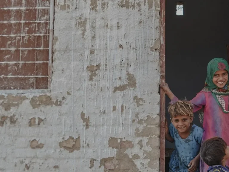 Three children in the doorway of a shelter in Pakistan