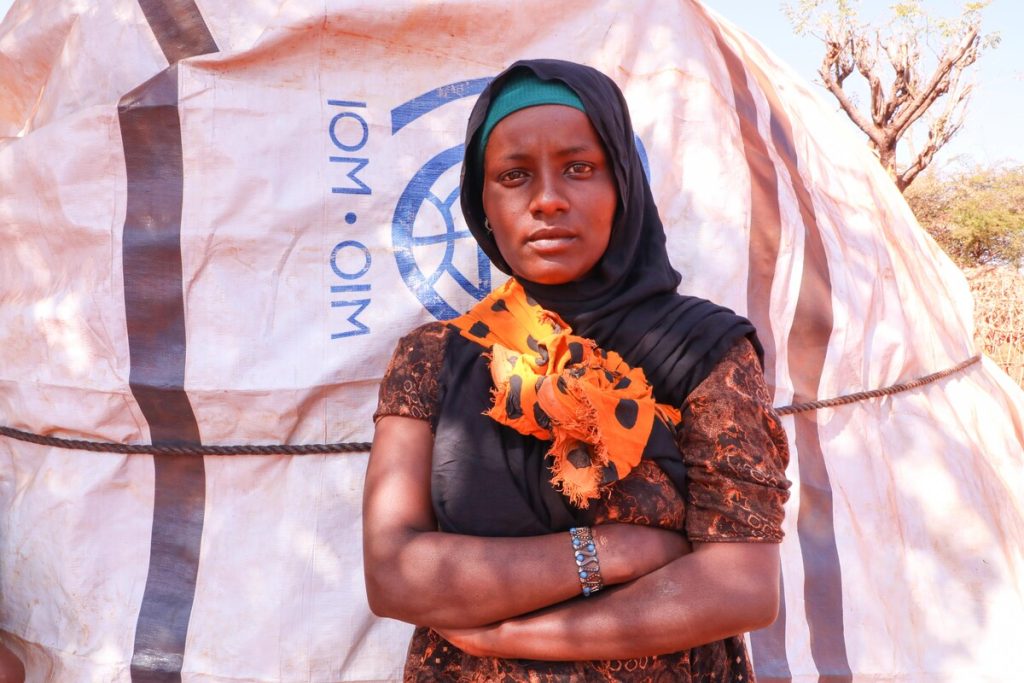 Woman standing outside a shelter covered in a tarpaulin in Ethiopia