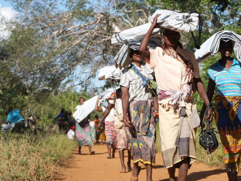 Woman carrying tarpaulins on their heads