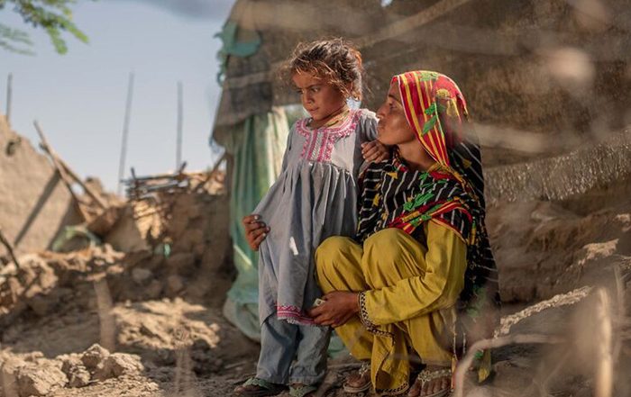 Woman and child among destroyed buildings after flooding in Pakistan